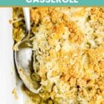 Canned asparagus casserole with peas and a spoon in a baking dish.