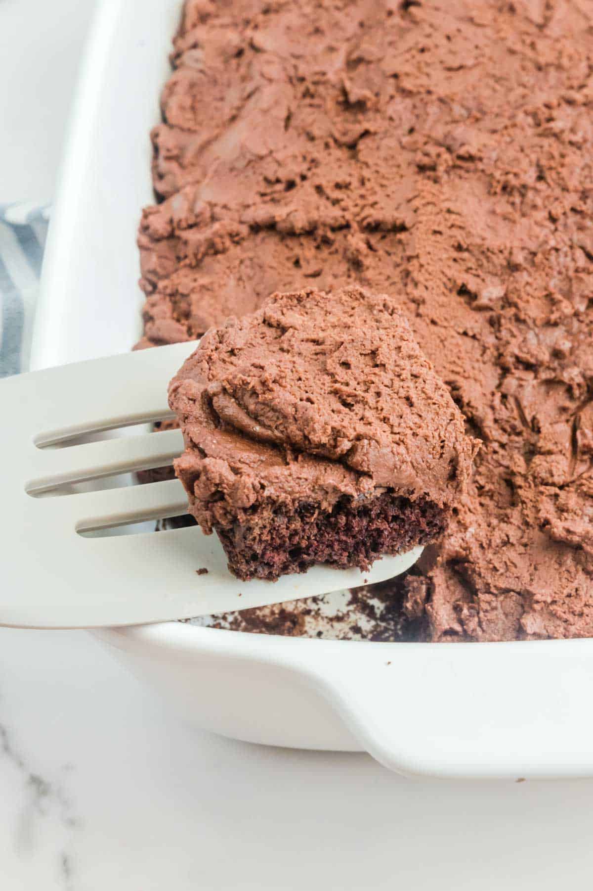 Chocolate Mayonnaise Cake in a baking dish and a slice of it on a spatula.