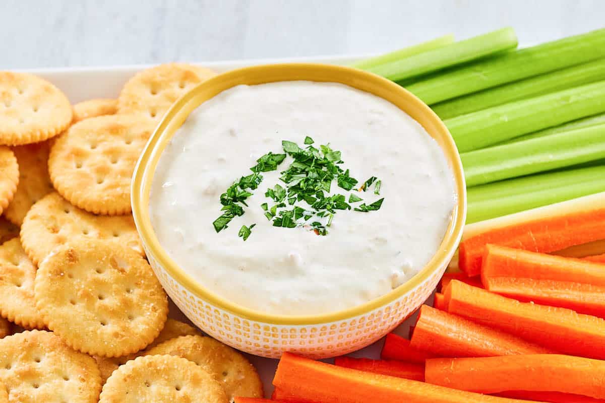 New England clam chowder dip on a platter with celery, carrots, and crackers.