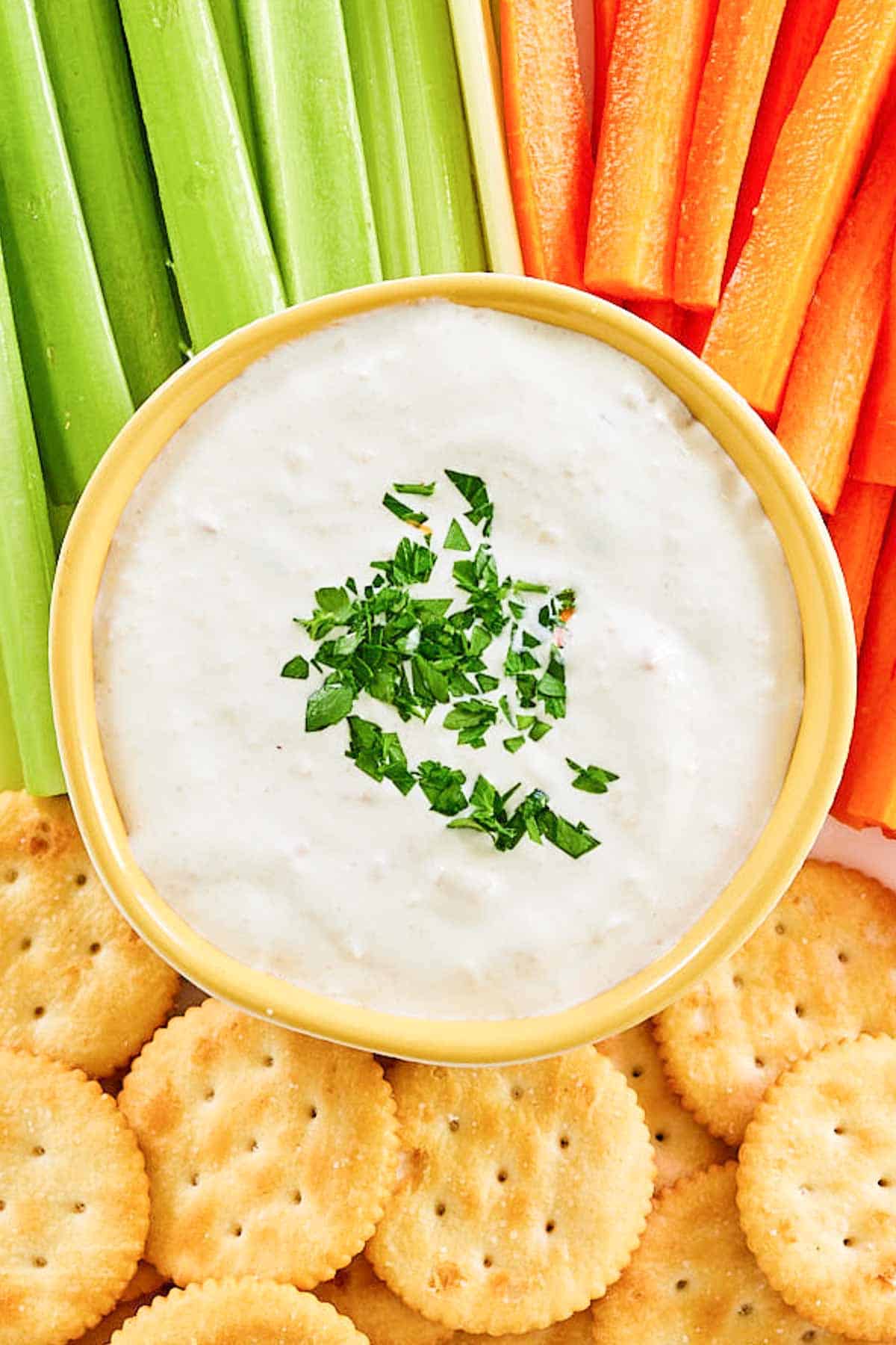 Overhead view of New England clam chowder dip, crackers, carrots, and celery.