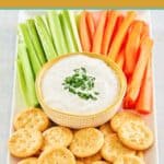 New England clam chowder dip on a platter with crackers and veggies.
