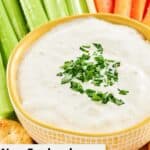 A bowl of New England clam chowder dip with celery, carrots, and crackers beside it.