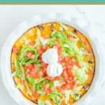 Overhead view of impossible taco pie topped with lettuce, tomatoes, and sour cream.