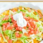 Impossible taco pie topped with lettuce, tomatoes, and sour cream.