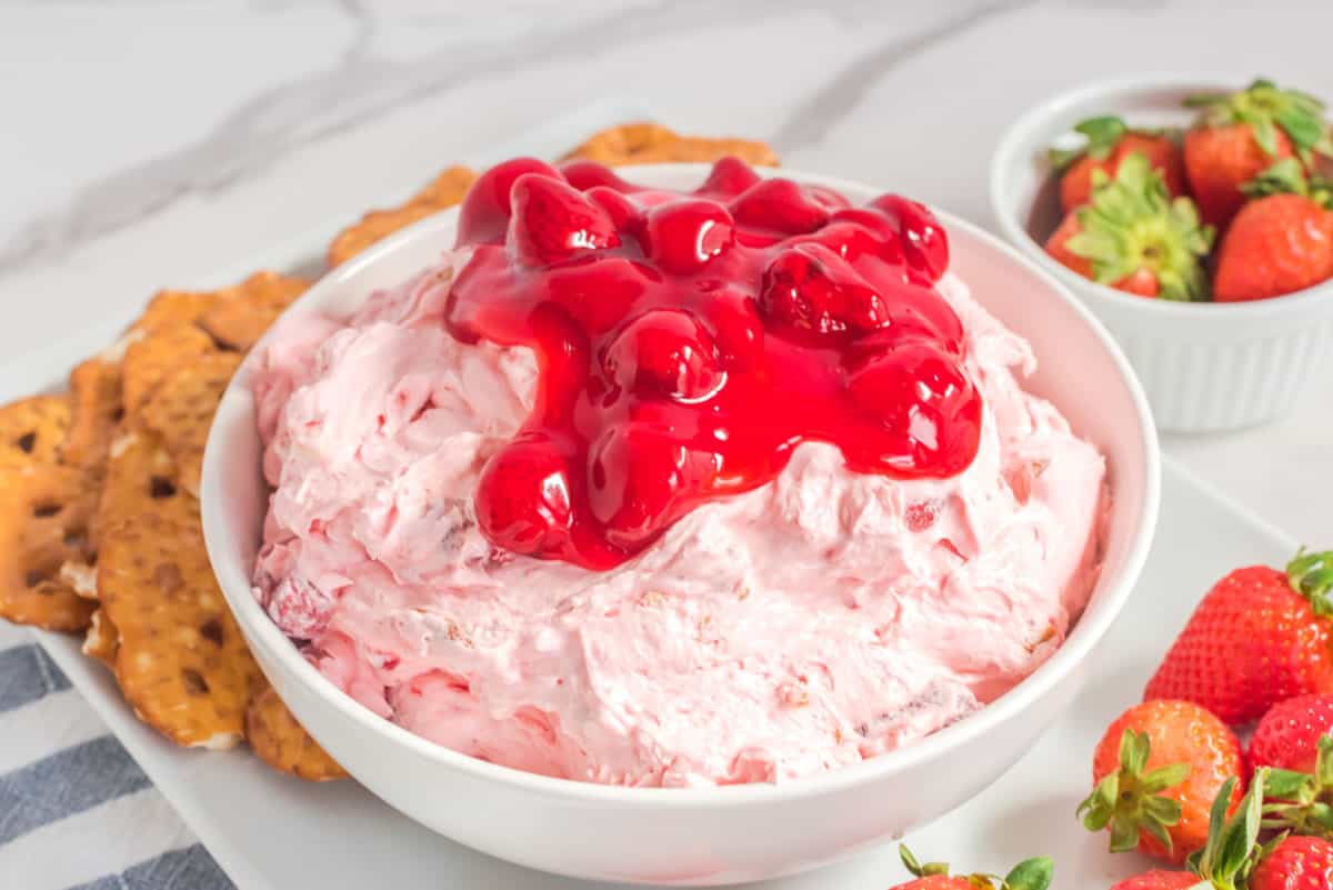 Strawberry pretzel dip on a platter with pretzel chips and strawberries.