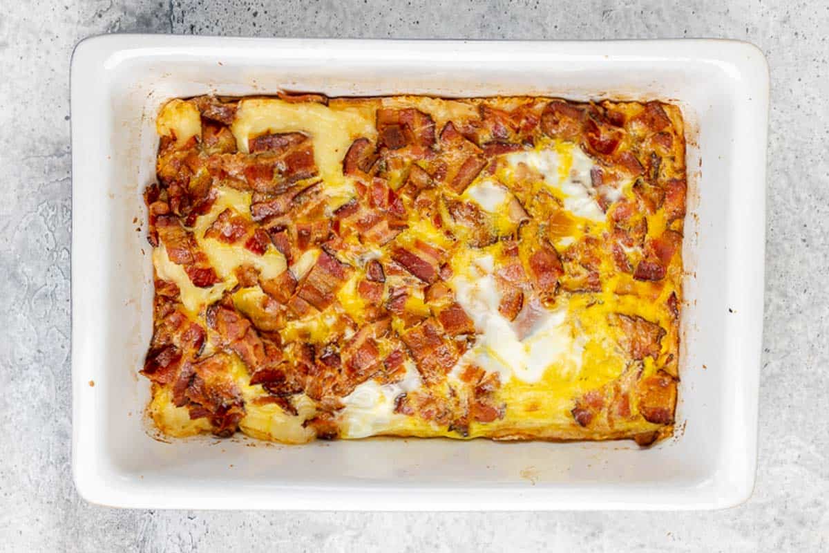 Overhead view of baked Swiss and bacon squares in a baking dish.