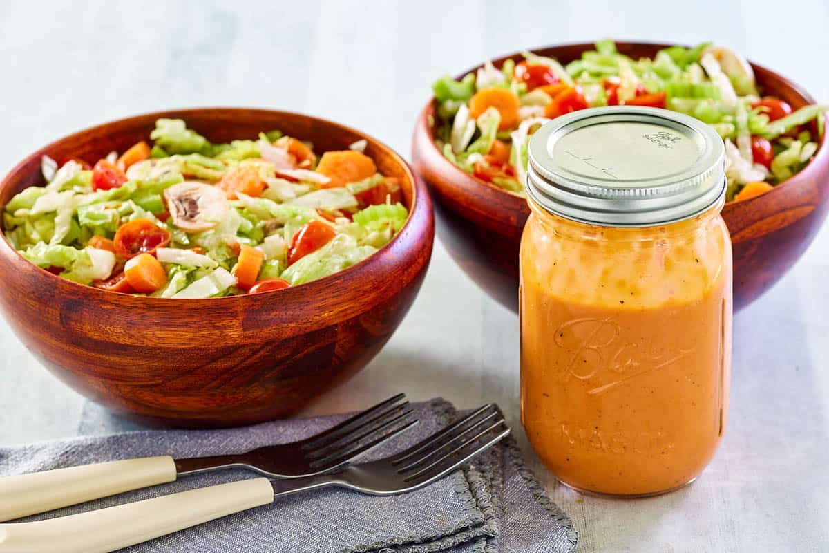 Campbell tomato soup French dressing in a mason jar and two bowls of salad.