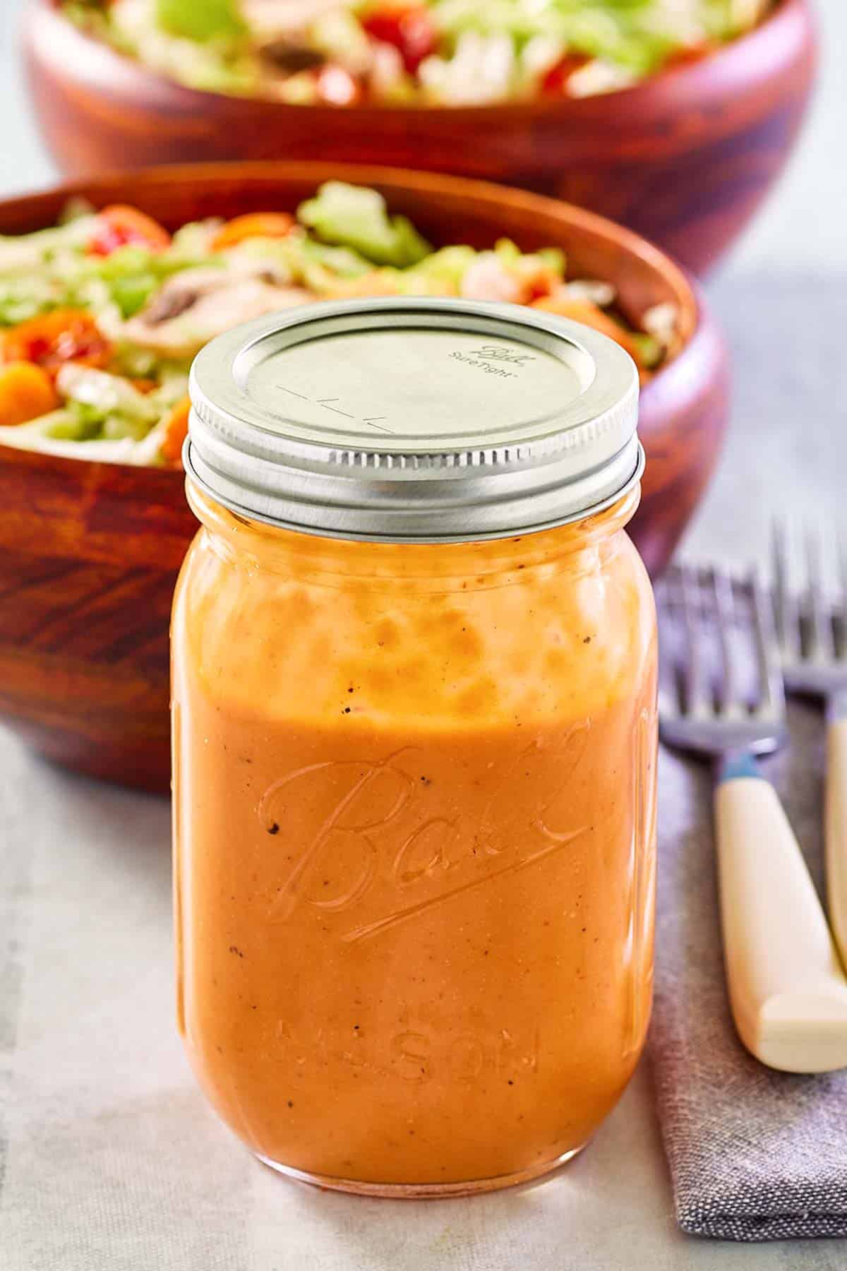 Campbell tomato soup French dressing in a mason jar and salads behind it.