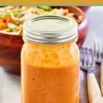 A jar of tomato soup French Dressing and a salad behind it.