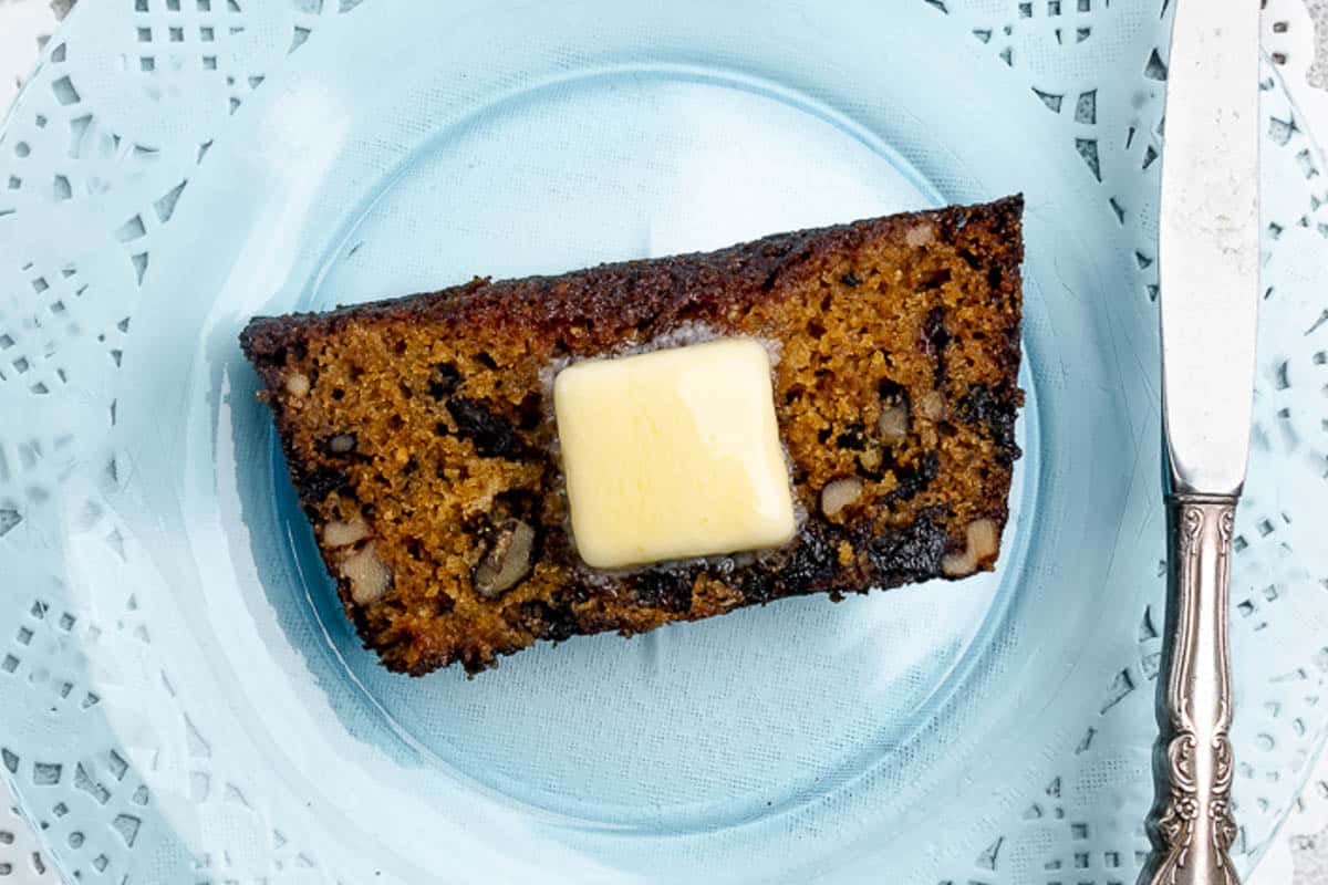 A slice of prune bread with a pat of butter on top of it.