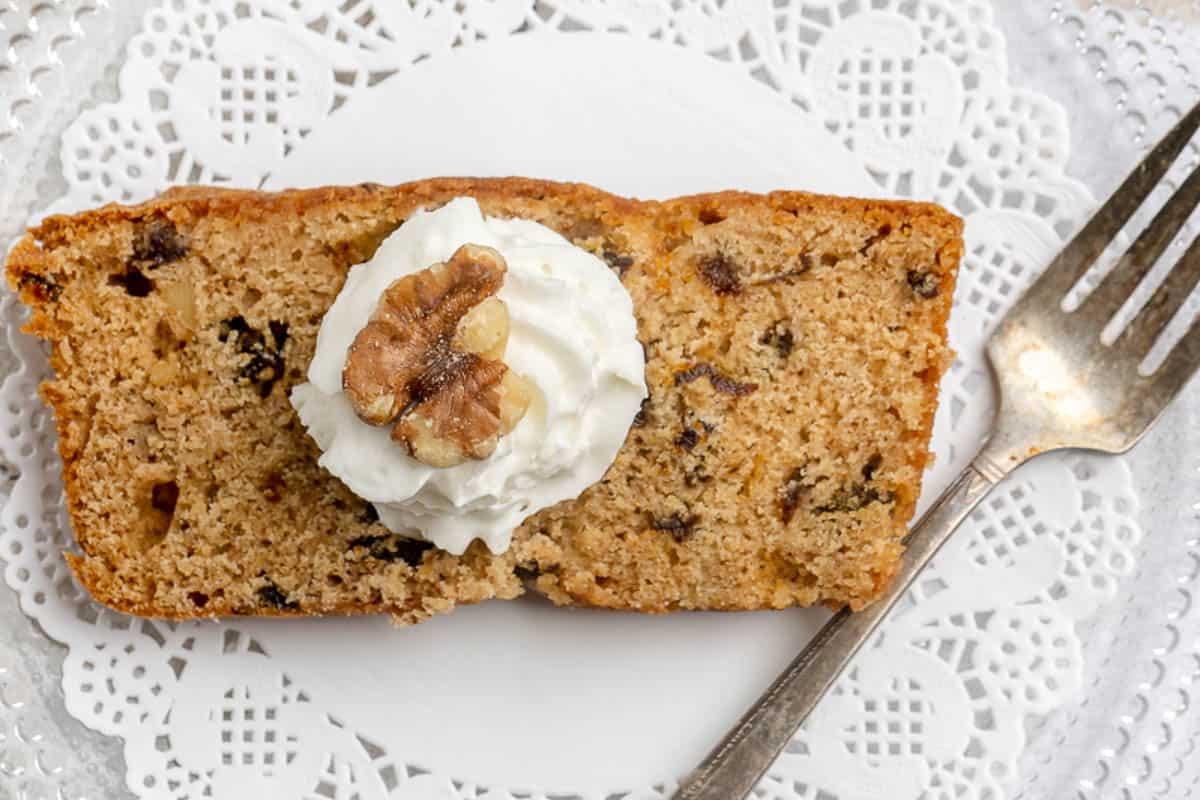 Overhead view of a prune cake slice topped with whipped cream and a walnut.
