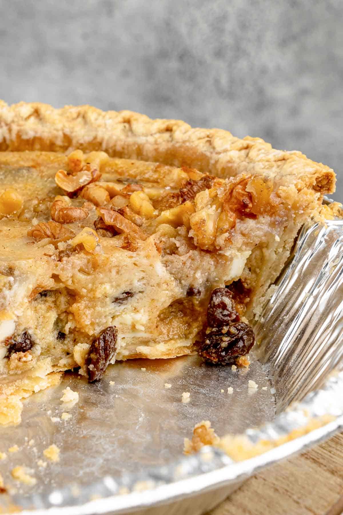 Closeup of sour cream raisin pie in a pie plate with slices cut out of it.