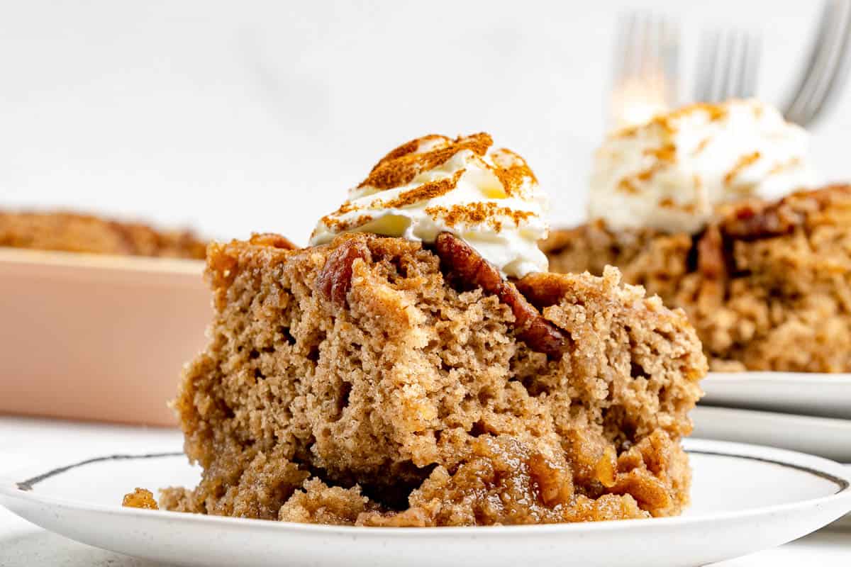 Cinnamon pecan pudding cake with whipped cream on top.