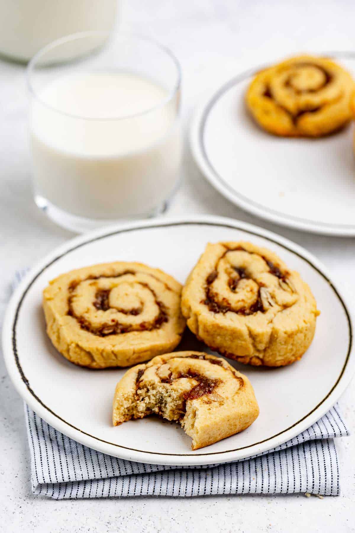 Date pinwheel cookies on a plate and a glass of milk.