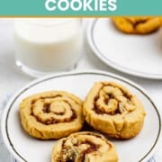 Three date pinwheel cookies on a plate and a glass of milk beside it.