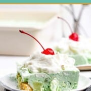 Lime jello salad serving topped with whipped cream and a cherry.