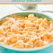 A bowl of orange Jello salad with cottage cheese and marshmallows.