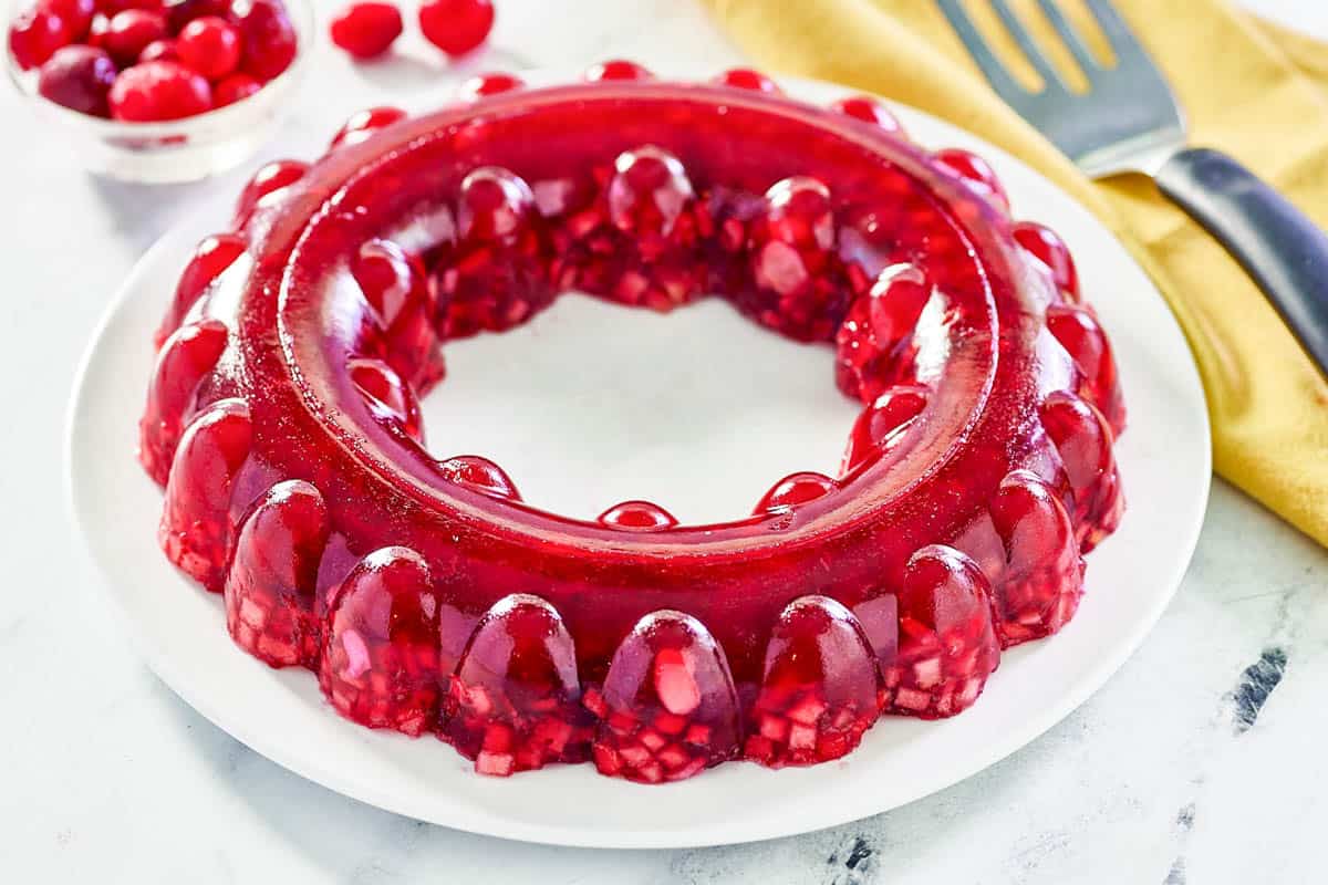 Cranberry jello salad on a large round platter and a bowl of cranberries.
