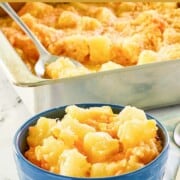 Pineapple cheese casserole in a baking dish and a serving in a bowl in front of it.