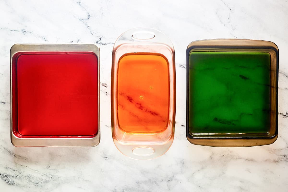 Strawberry, orange, and lime jello in separate pans.