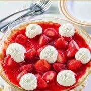Strawberry pie garnished with dollops of whipped cream.