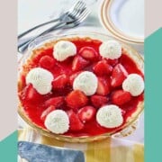 Fresh strawberry pie topped with dollops of whipped cream.