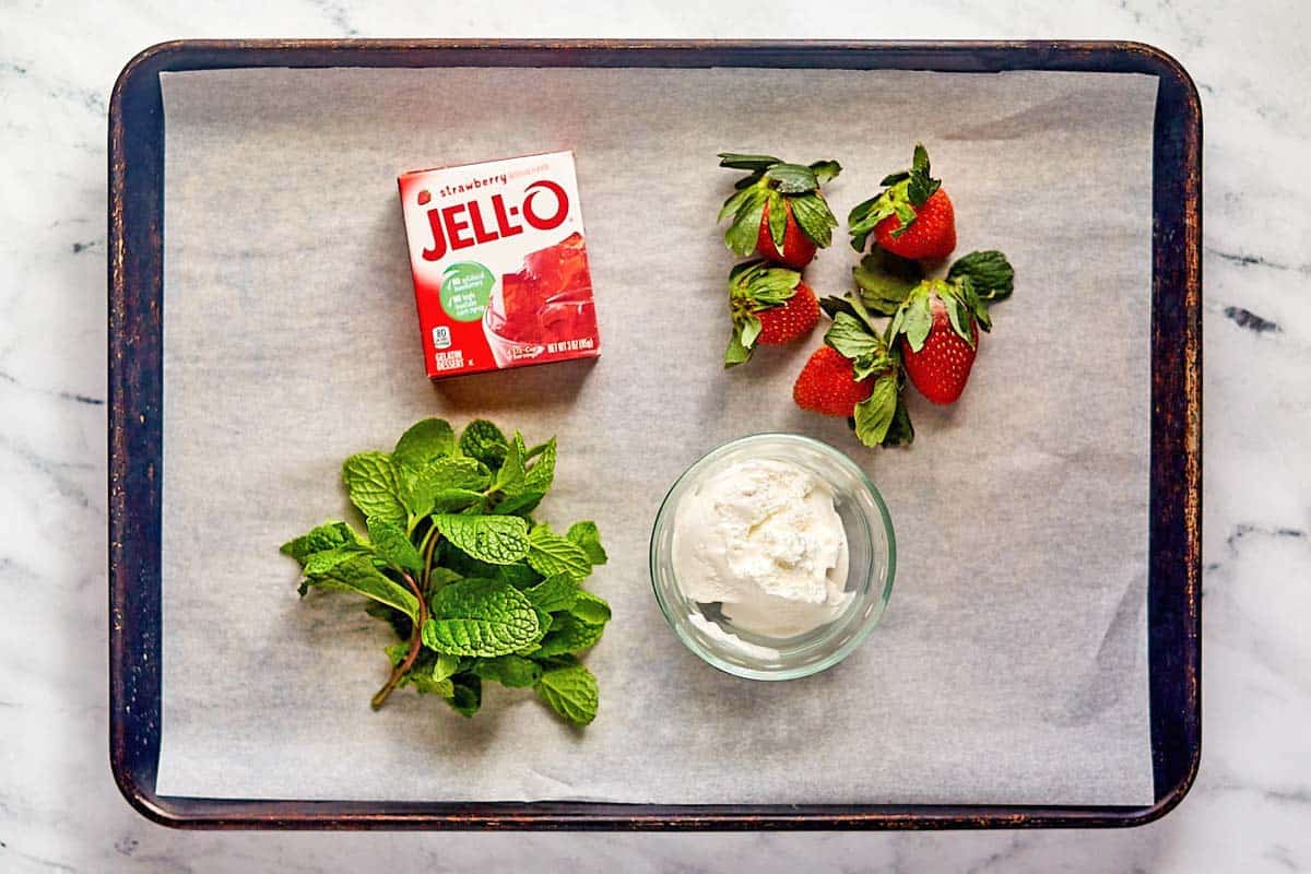 Strawberry jello parfait ingredients on a tray.