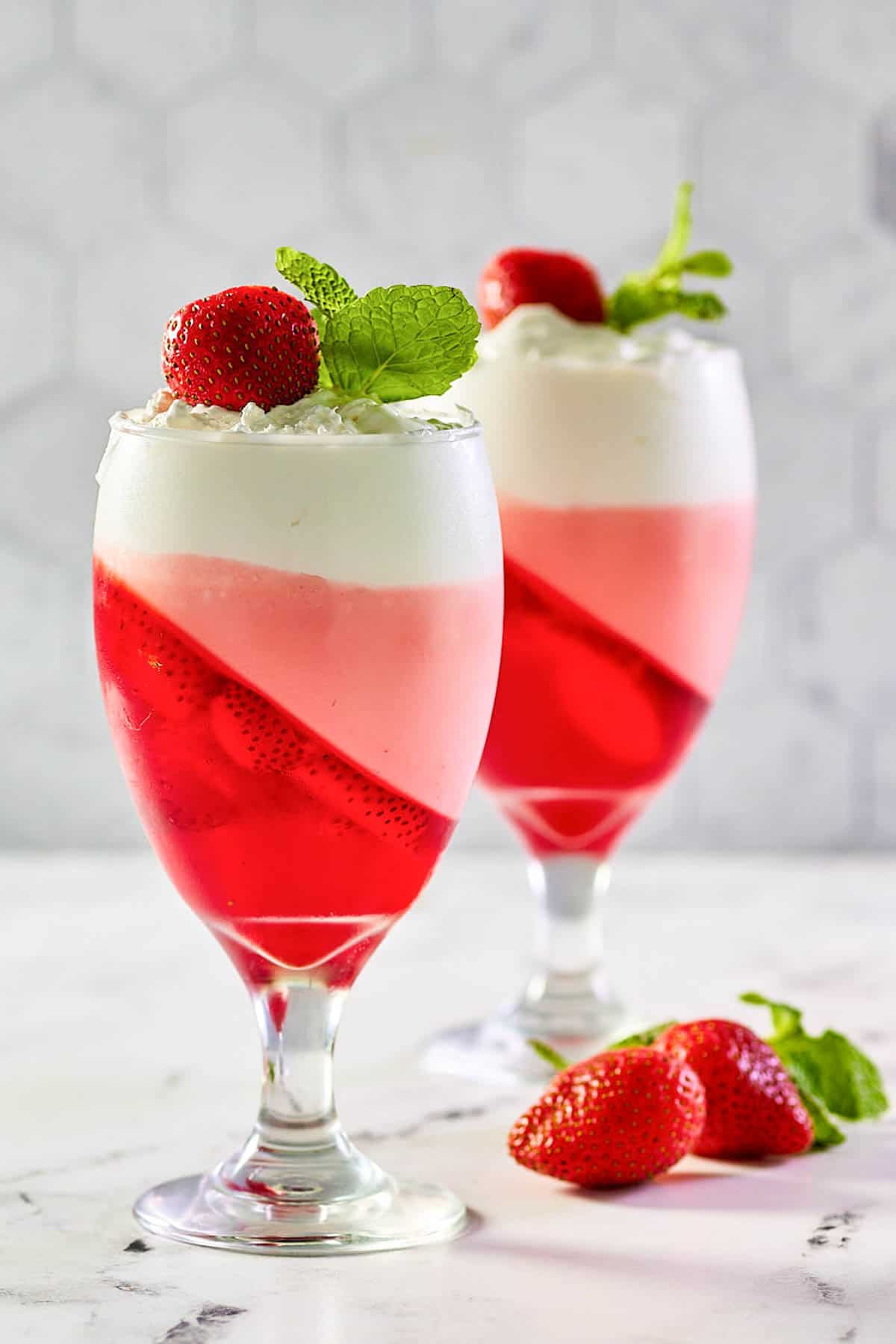 Strawberry jello parfait garnished with a whole strawberry and fresh mint.