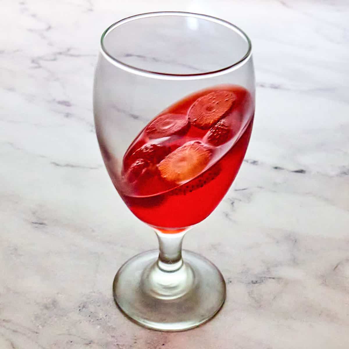 Fresh strawberry slices and strawberry jello in a glass.