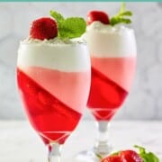 Strawberry jello parfait in two glasses and fresh strawberries next to them.