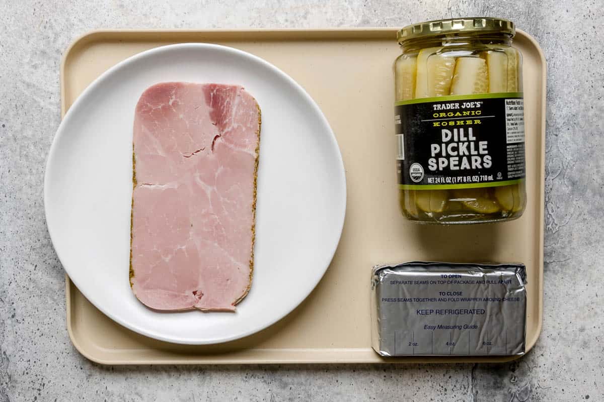 Ham and pickle roll ups ingredients on a tray.