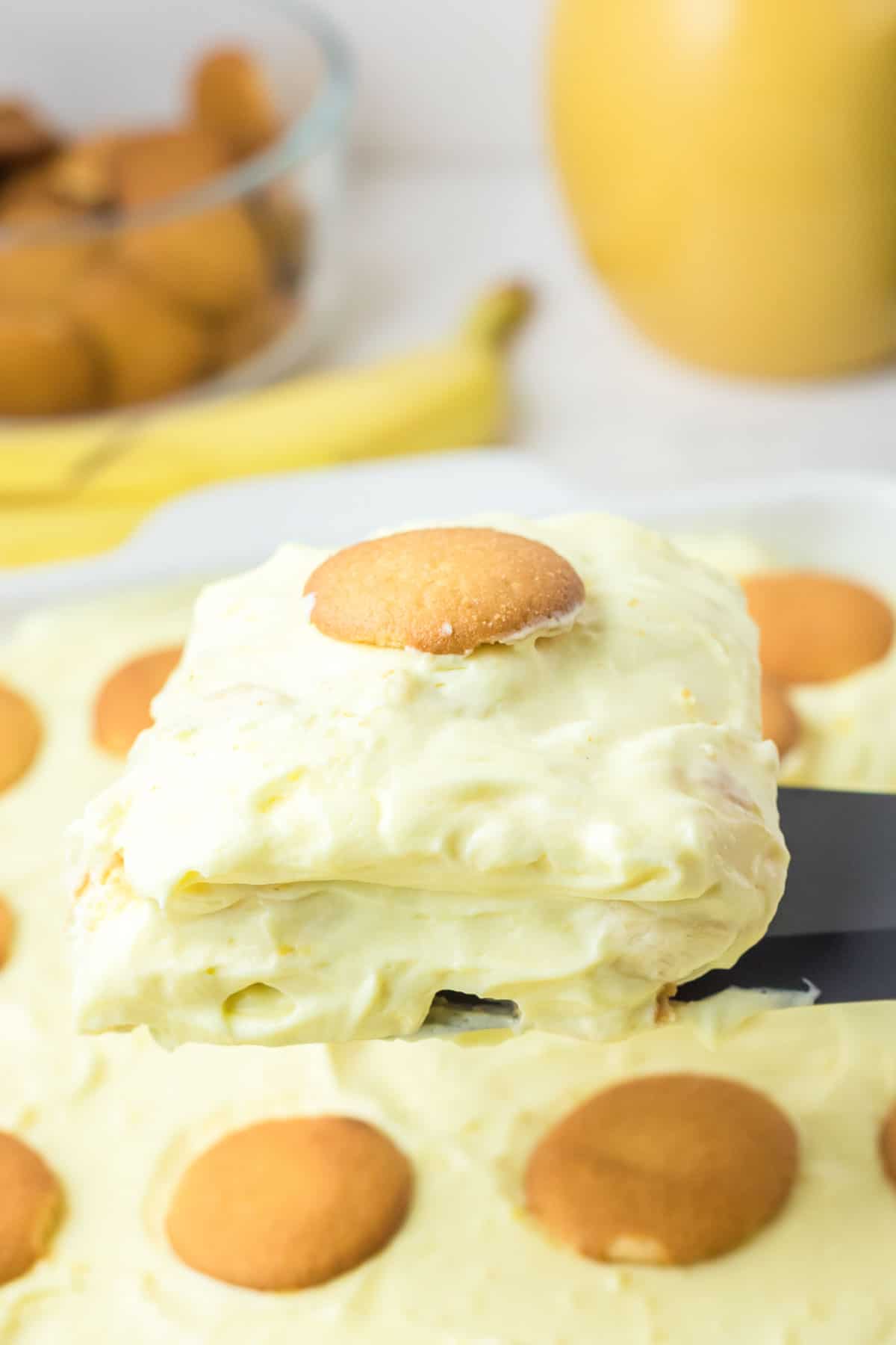 Banana pudding with sour cream serving on a spatula over the dessert.