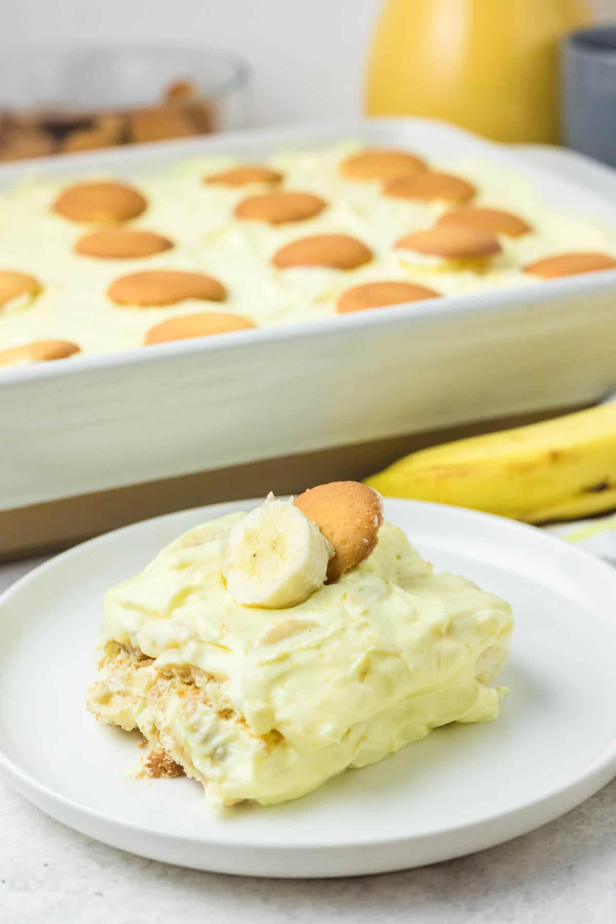 Banana pudding with sour cream on a plate and in a serving dish.