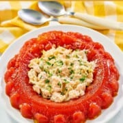 Tomato aspic with shrimp salad in the center on a round platter.
