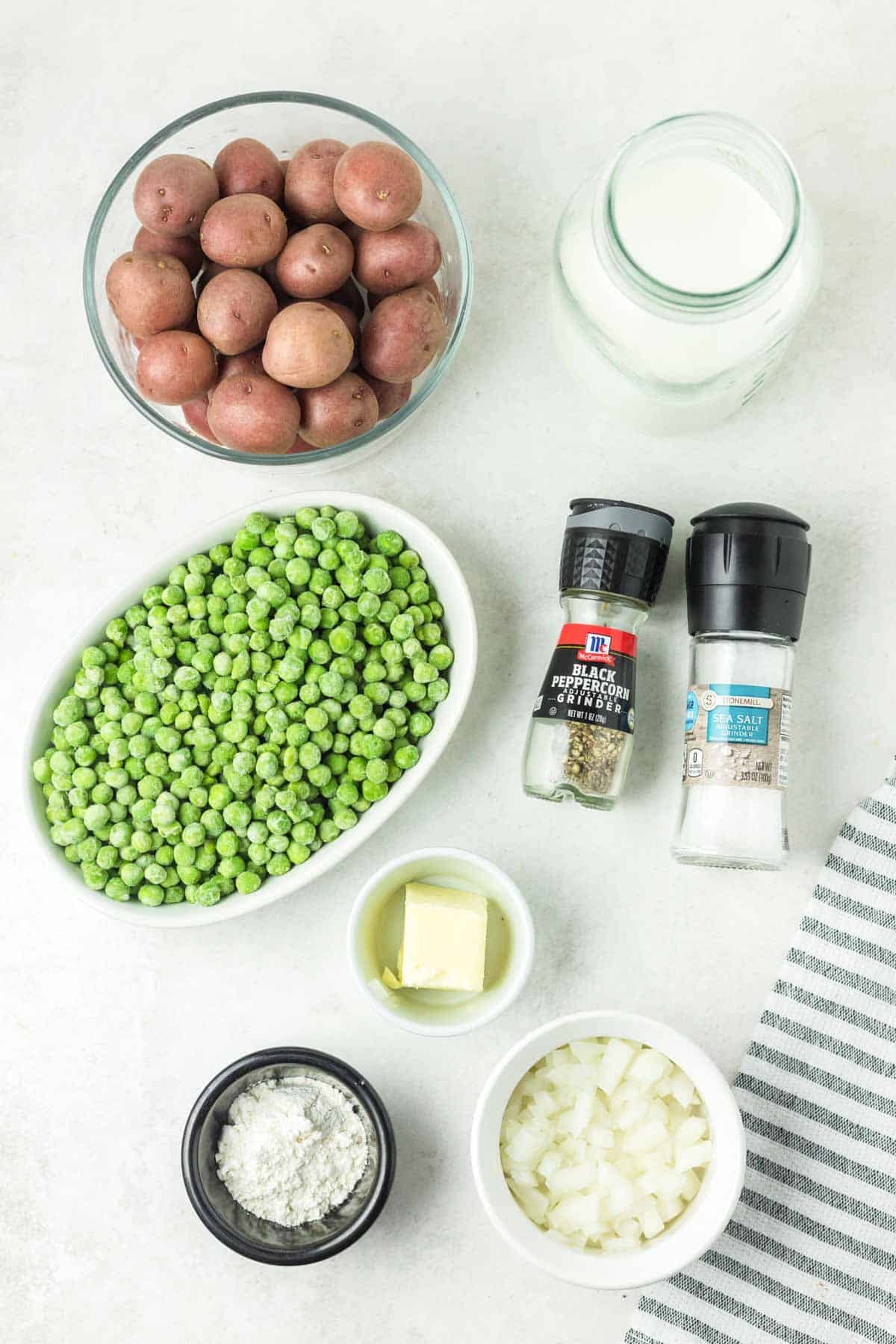 Creamed peas and potatoes ingredients on a marble surface.