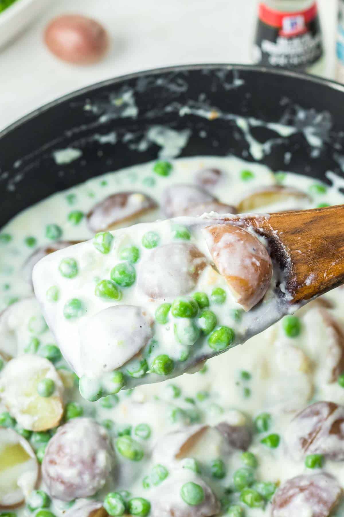 Creamed peas and potatoes on a wooden spoon.