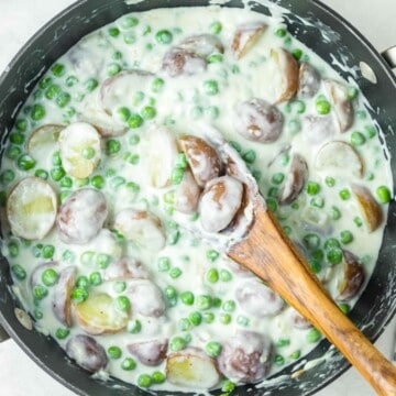 Creamed peas and potatoes in a skillet.